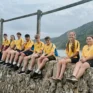Junior Boscastle and Crackington rowing crew sit on harbour wall, beach in background